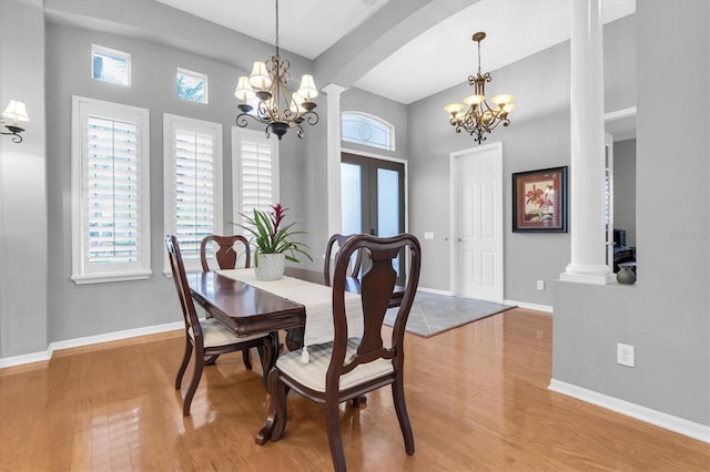 dining room with ornate columns, light wood finished floors, and a notable chandelier