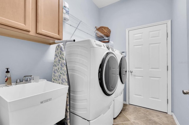 clothes washing area featuring washing machine and clothes dryer, light tile patterned floors, cabinet space, a sink, and baseboards