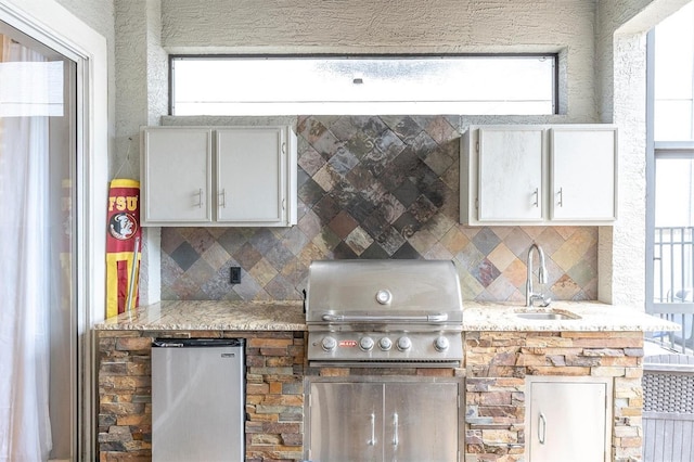 kitchen featuring tasteful backsplash, fridge, a sink, and white cabinetry