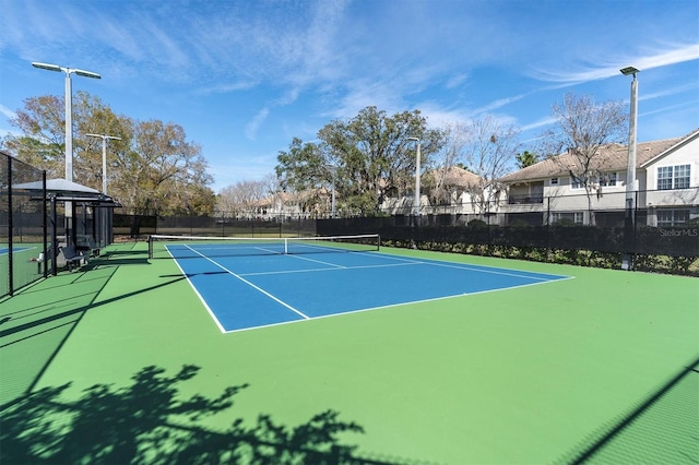 view of tennis court with community basketball court and fence