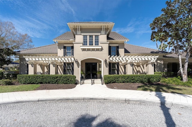 view of front of home featuring a tile roof, a pergola, and stucco siding