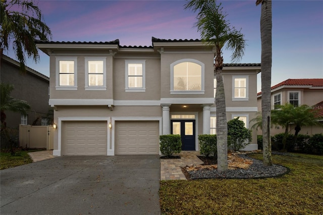 view of front of home featuring stucco siding, driveway, a tile roof, fence, and a garage