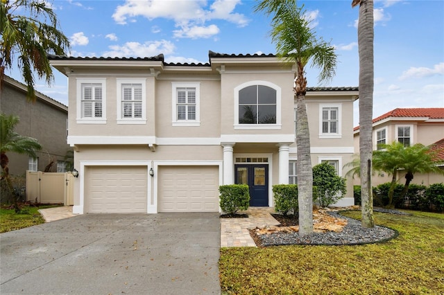 mediterranean / spanish house with stucco siding, concrete driveway, a garage, and fence