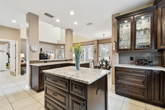 kitchen with dark brown cabinetry, light tile patterned floors, visible vents, and backsplash