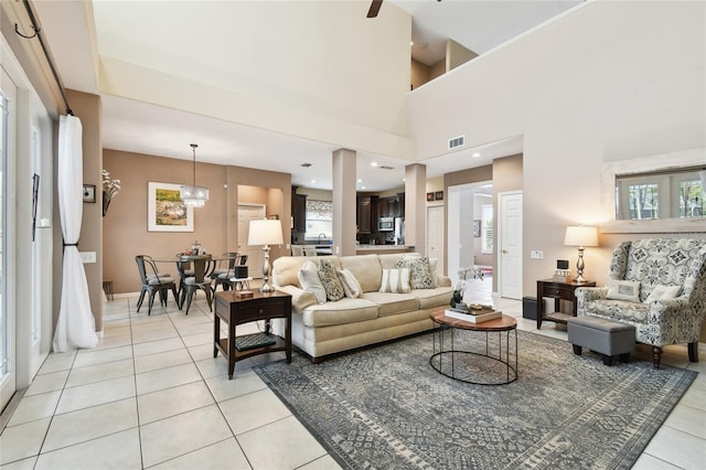 living area featuring visible vents, a high ceiling, light tile patterned floors, baseboards, and a chandelier