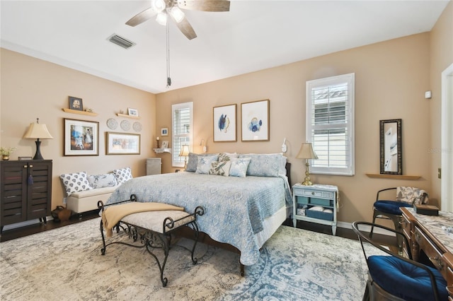 bedroom with multiple windows, wood finished floors, visible vents, and baseboards