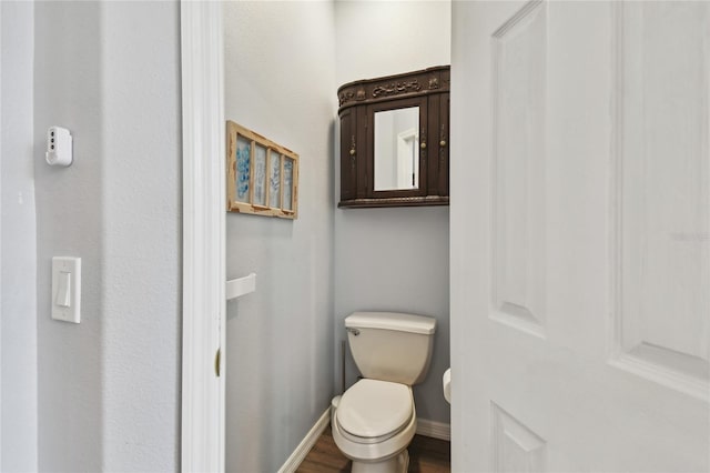 bathroom featuring toilet, wood finished floors, and baseboards