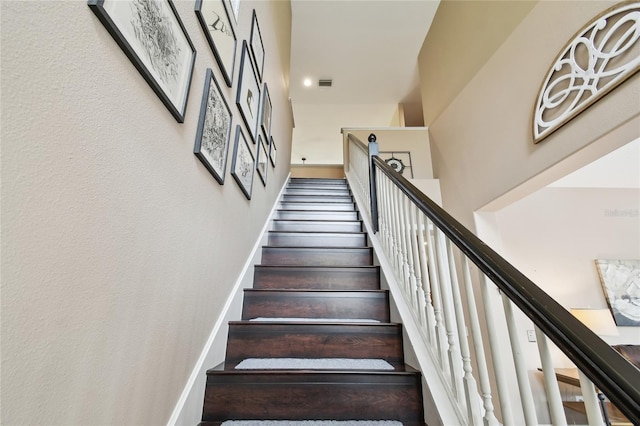 stairs featuring visible vents, baseboards, and a towering ceiling