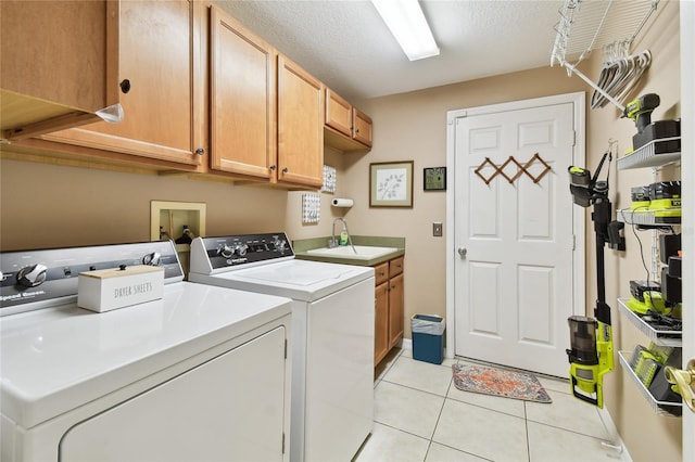 laundry room with a sink, a textured ceiling, cabinet space, separate washer and dryer, and light tile patterned floors