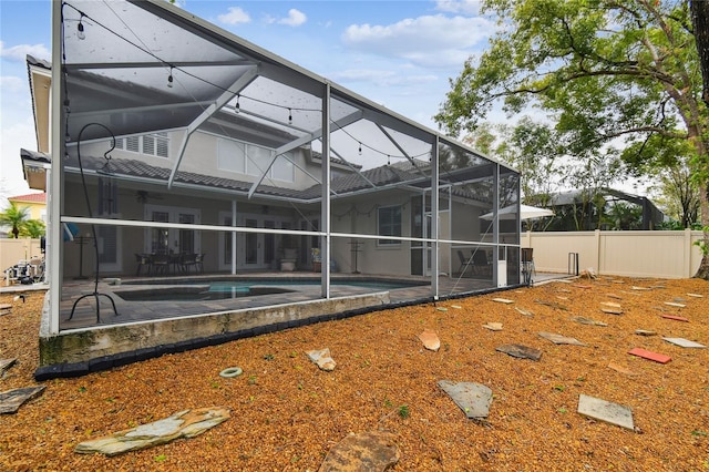 back of property featuring a patio, fence, an outdoor pool, french doors, and a lanai