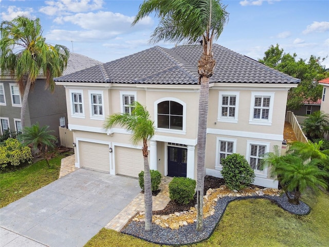 view of front facade with a tiled roof, an attached garage, driveway, and stucco siding