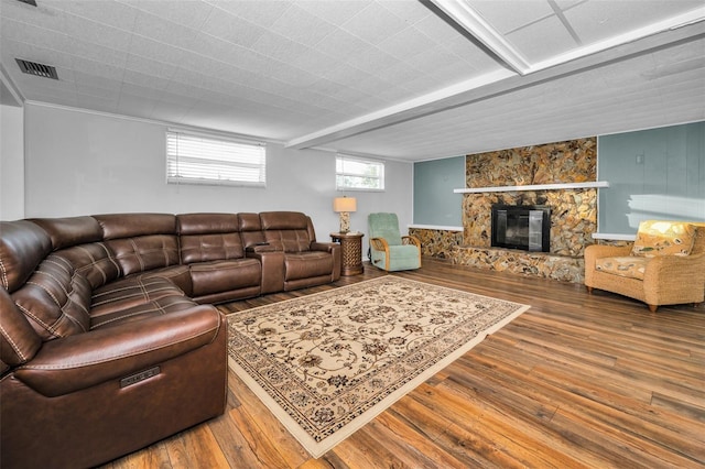 living area with visible vents, wood finished floors, and a stone fireplace