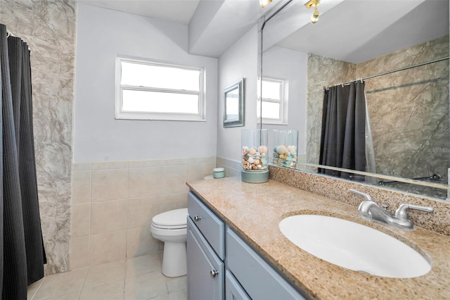 full bath with tile patterned flooring, plenty of natural light, tile walls, and vanity