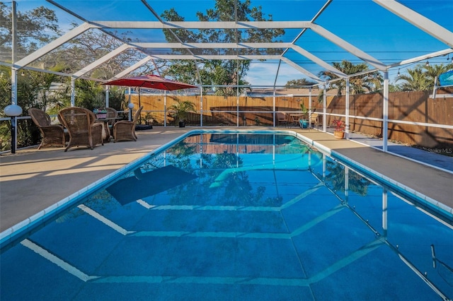 view of pool featuring glass enclosure, a patio, a fenced backyard, and a fenced in pool