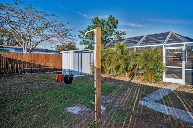 view of yard featuring an outbuilding, a shed, a fenced backyard, and a lanai