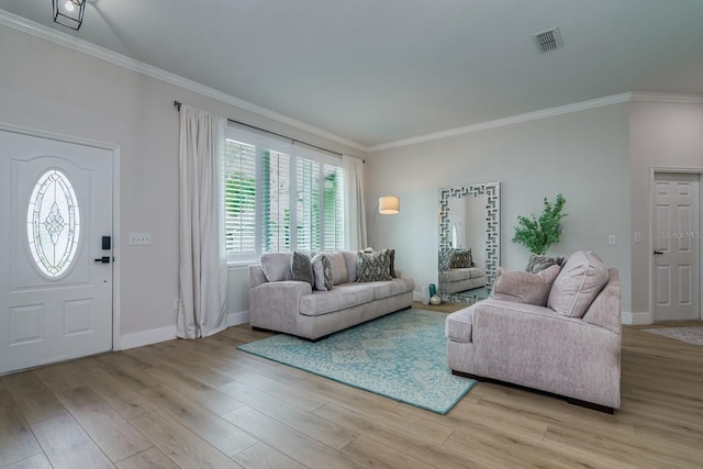 living room with ornamental molding, light wood-style flooring, visible vents, and baseboards