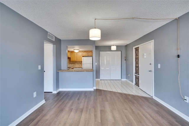 unfurnished living room featuring visible vents, baseboards, and wood finished floors