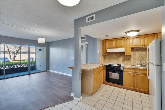 kitchen with visible vents, black electric range oven, freestanding refrigerator, light countertops, and under cabinet range hood