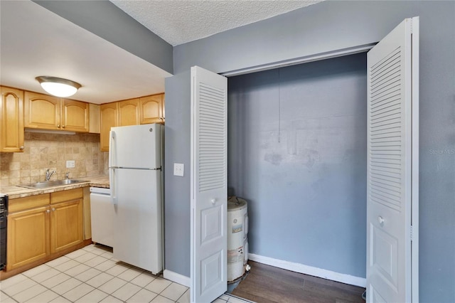 kitchen featuring decorative backsplash, a sink, a textured ceiling, white appliances, and baseboards