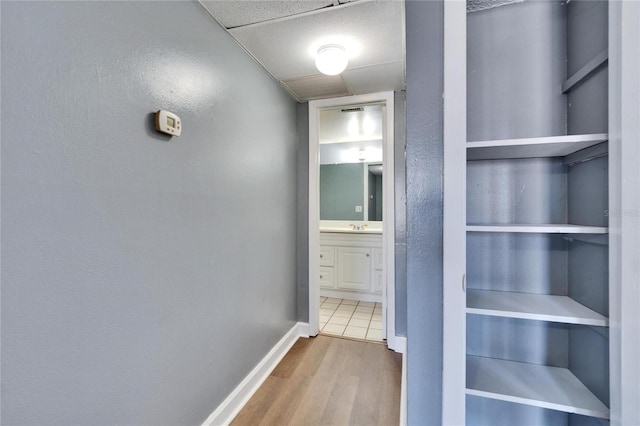 corridor with a sink, baseboards, and wood finished floors