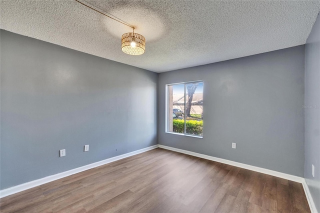 spare room with dark wood finished floors, a textured ceiling, and baseboards