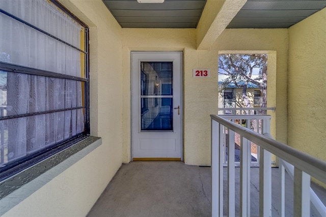 entrance to property with a balcony and stucco siding