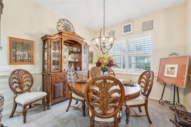 dining area with a chandelier, light colored carpet, and baseboards