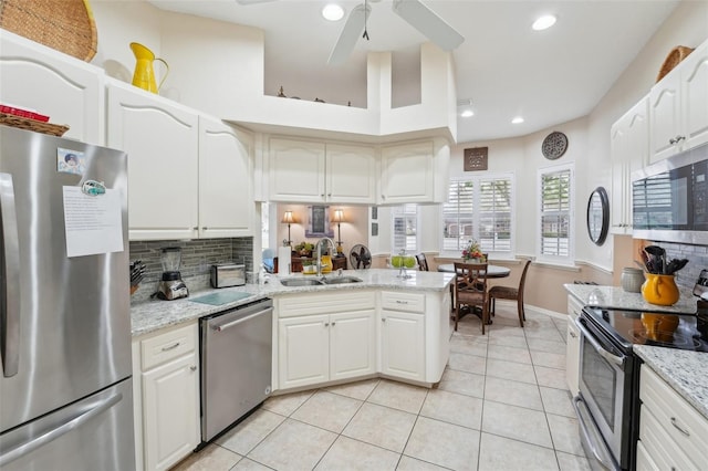 kitchen with light stone countertops, appliances with stainless steel finishes, white cabinets, and a sink