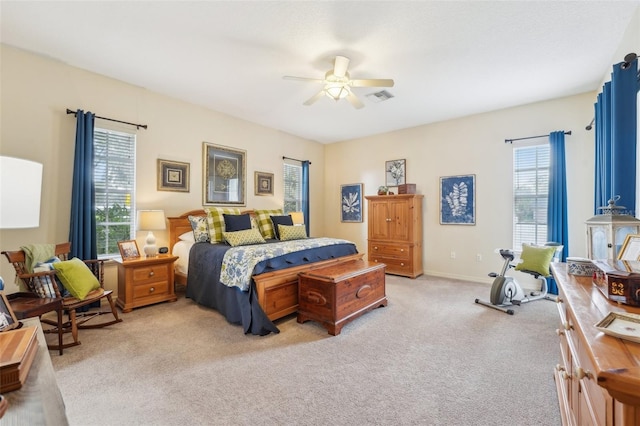 bedroom with light carpet, ceiling fan, visible vents, and baseboards