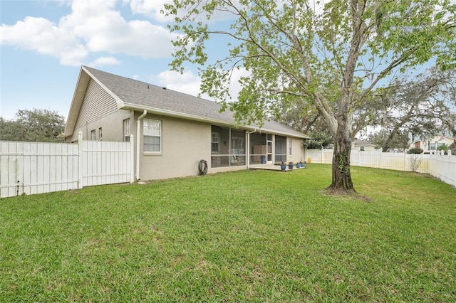 back of property featuring a sunroom, a fenced backyard, roof with shingles, a yard, and stucco siding