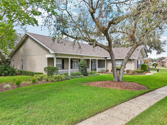 ranch-style home featuring roof with shingles, a front lawn, and stucco siding