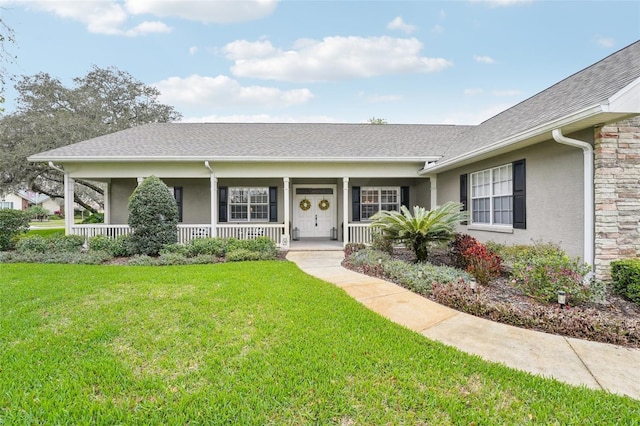 ranch-style house featuring a porch, a shingled roof, stone siding, stucco siding, and a front lawn