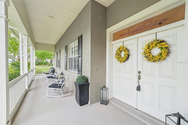 entrance to property with covered porch and stucco siding