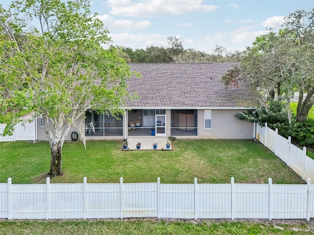 view of front facade featuring roof with shingles, stucco siding, a front yard, a sunroom, and a fenced backyard