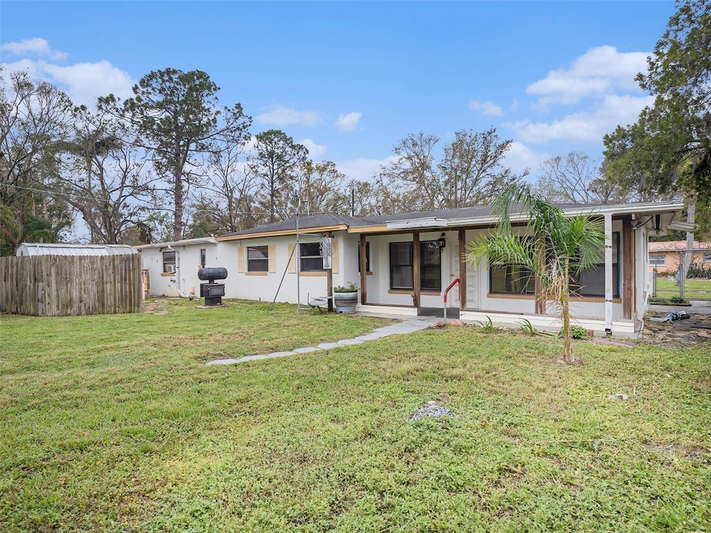 view of front facade with a front yard, fence, and stucco siding