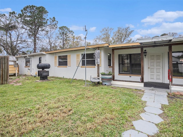 rear view of house with a yard and stucco siding