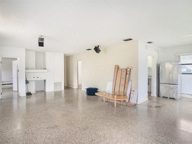 garage with visible vents, freestanding refrigerator, and baseboards