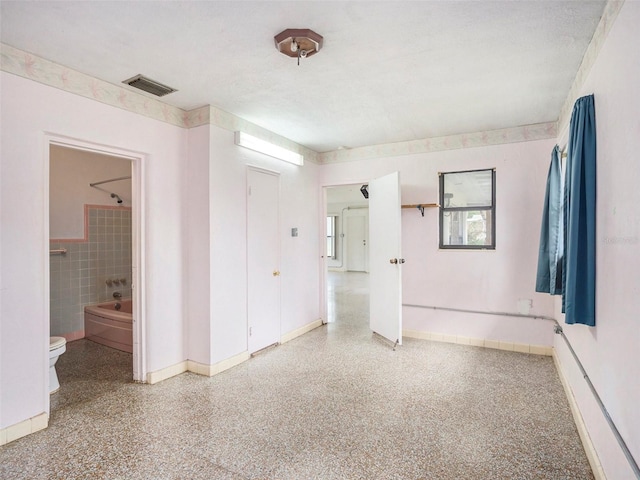 spare room featuring visible vents, tile walls, a textured ceiling, and speckled floor