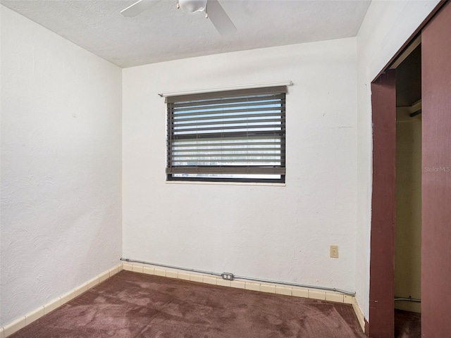 unfurnished bedroom with a ceiling fan, baseboards, carpet flooring, and a textured wall