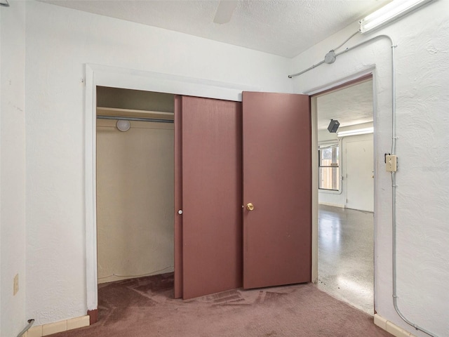 interior space with a textured wall, a closet, ceiling fan, and a textured ceiling