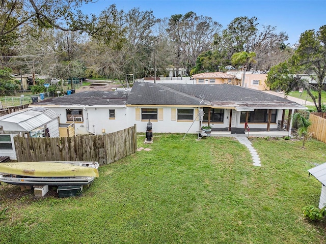 rear view of house with a lawn and fence