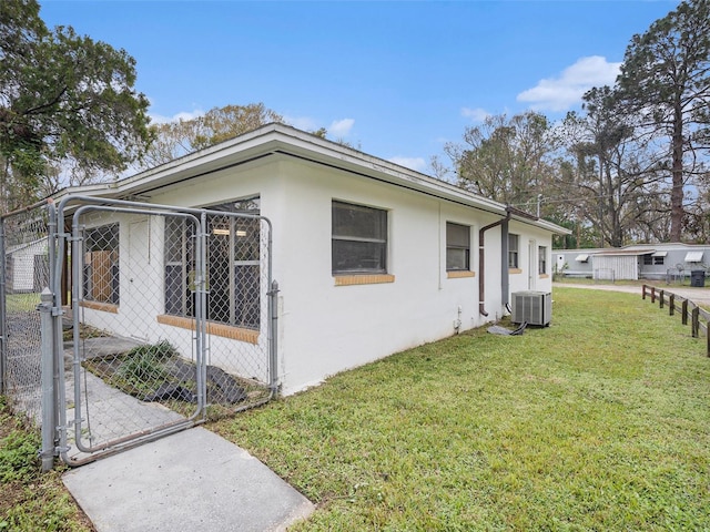 view of home's exterior featuring a yard, a gate, central AC, and stucco siding