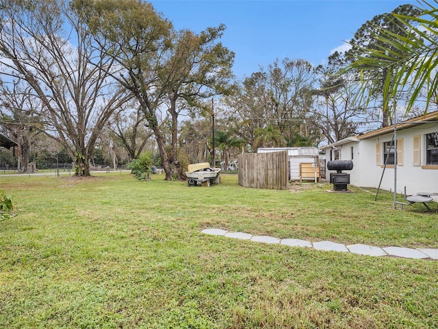 view of yard featuring an outbuilding, fence, and a storage unit