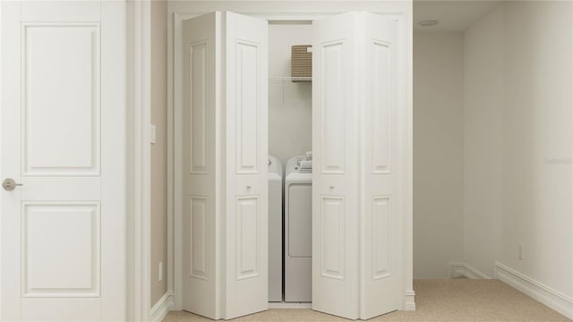 clothes washing area featuring laundry area, washing machine and dryer, and light colored carpet