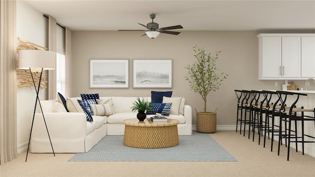 living area with a ceiling fan, light carpet, and baseboards