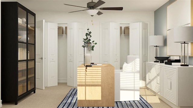 interior space with ceiling fan, two closets, and light colored carpet