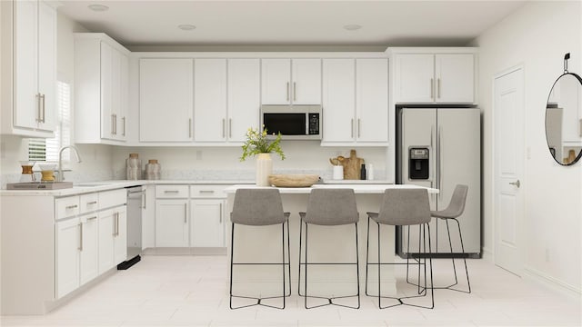 kitchen featuring light countertops, appliances with stainless steel finishes, a kitchen island, and white cabinetry