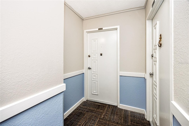 doorway to outside with a textured wall and baseboards