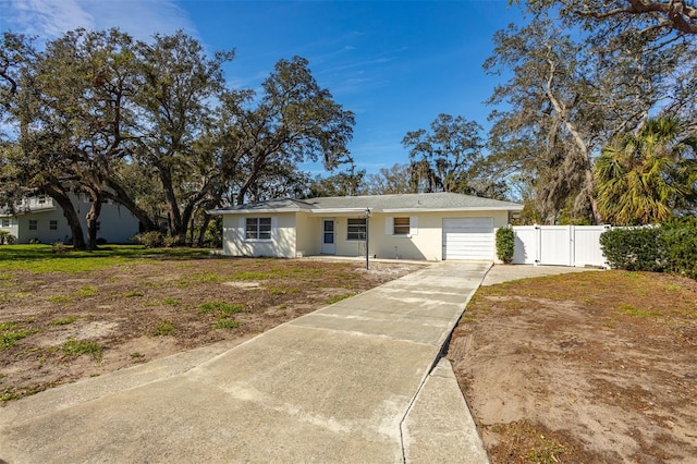 ranch-style home with driveway, stucco siding, an attached garage, fence, and a front yard