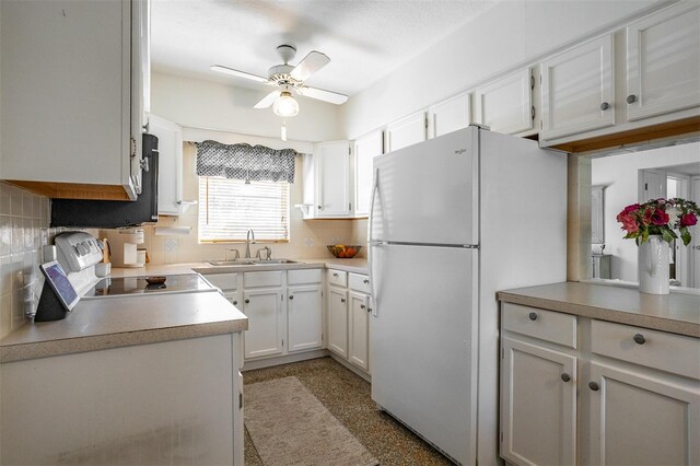 kitchen with light countertops, decorative backsplash, freestanding refrigerator, white cabinetry, and a sink